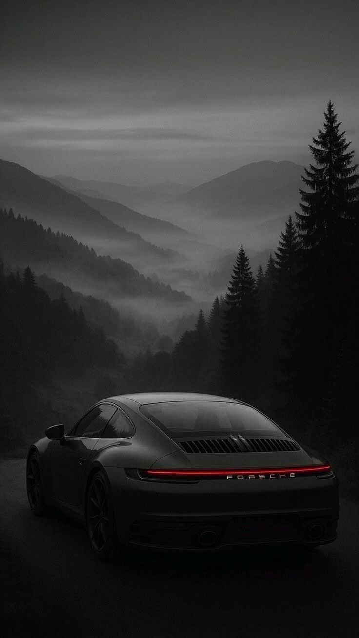 a black and white photo of a car in the middle of a foggy forest
