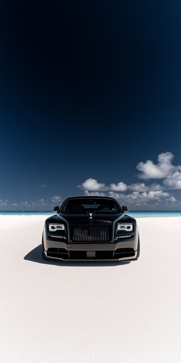 a black car is parked in the middle of an empty field with blue sky and clouds