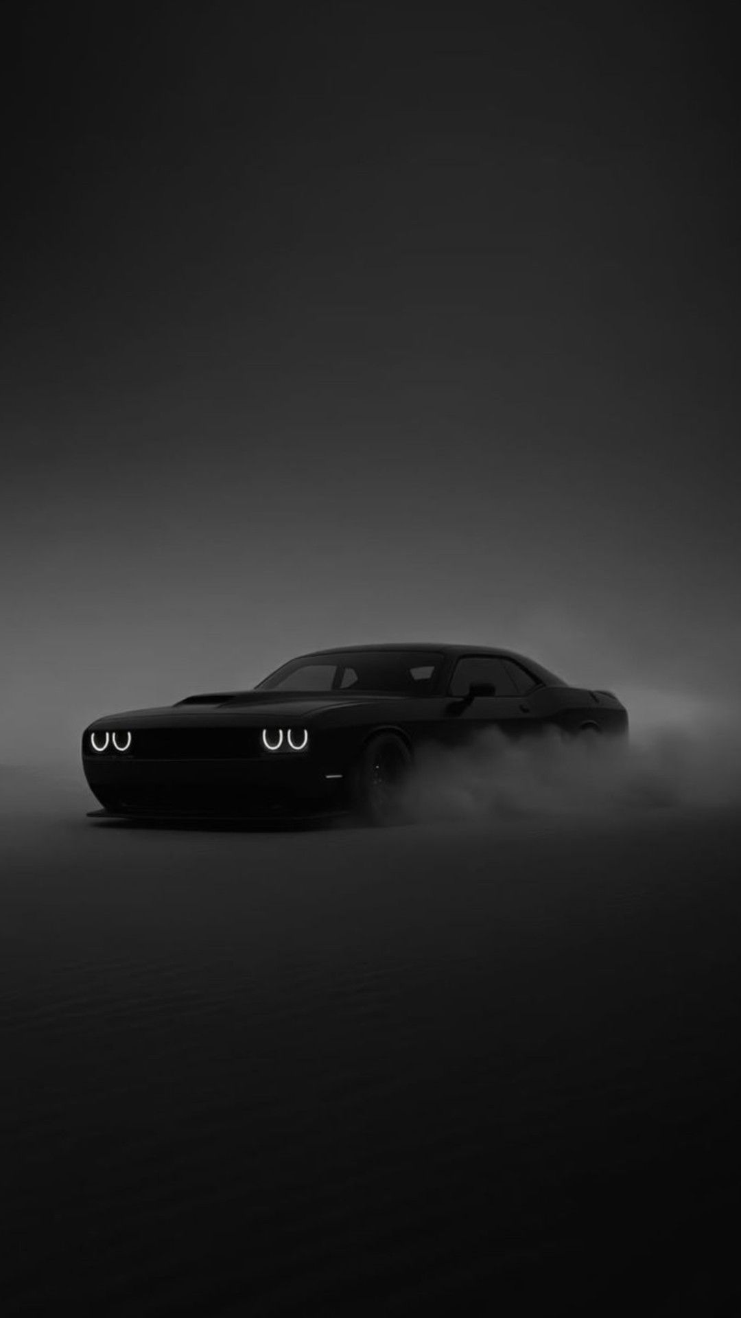 a black car with two eyes on it's face is in the middle of a foggy field