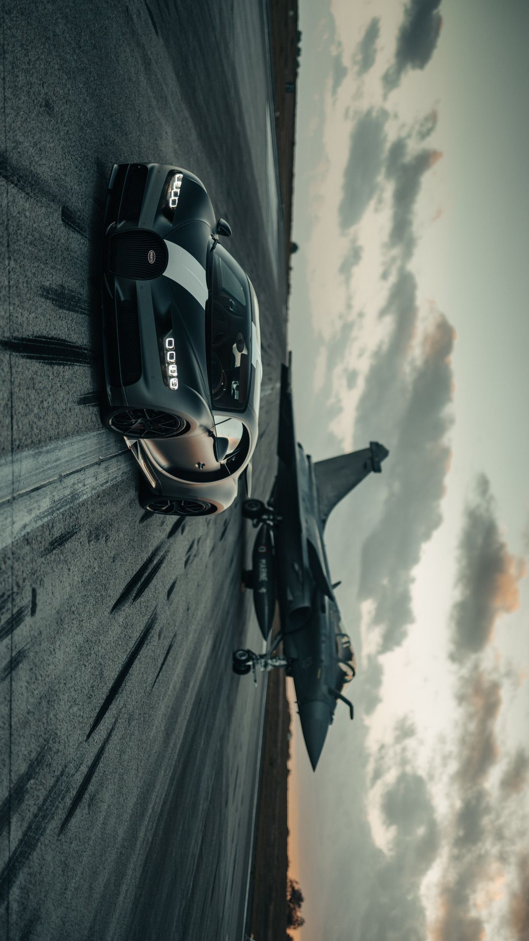 a black motorcycle parked on the side of a road with clouds in the sky behind it