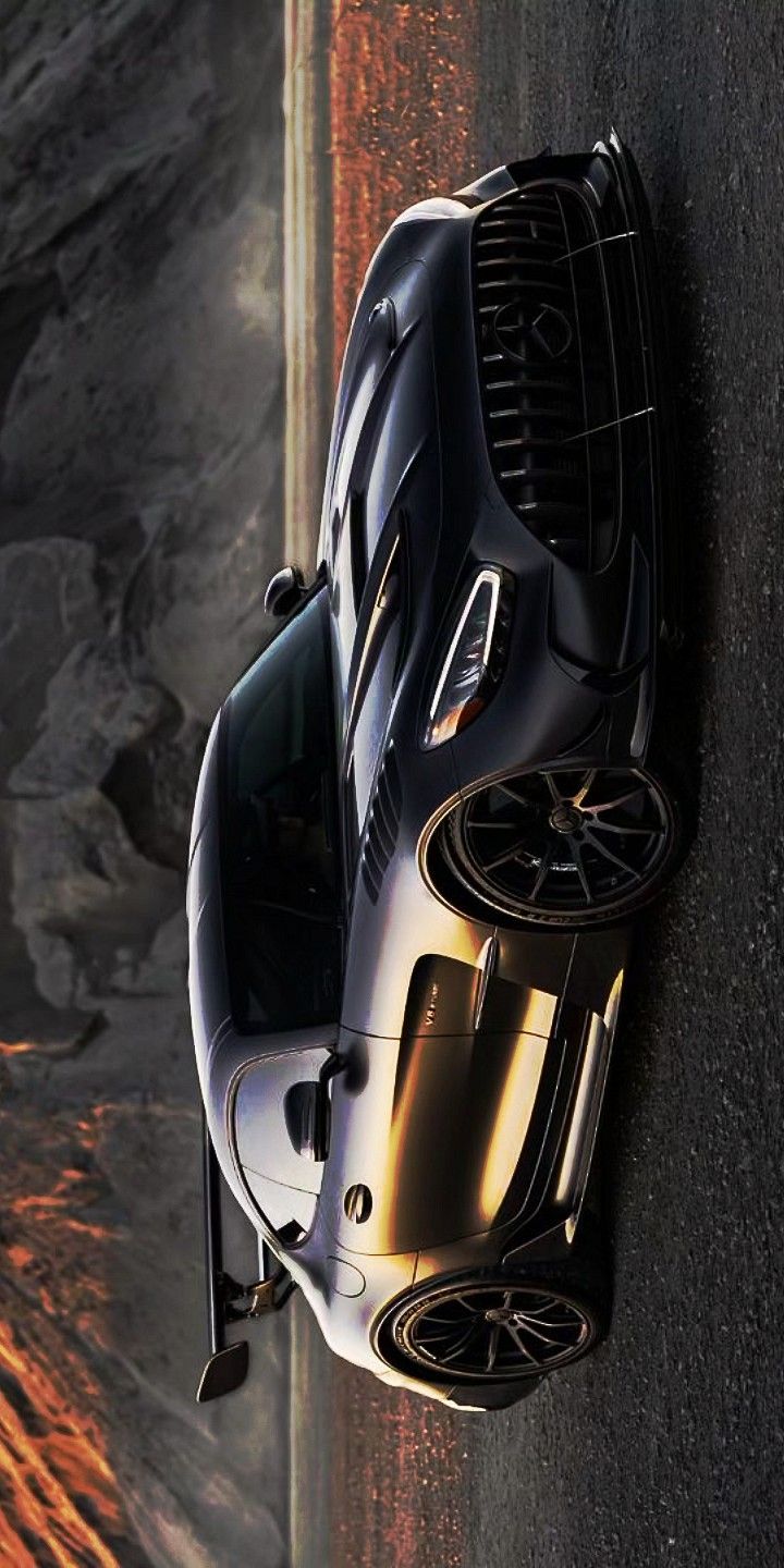 a black sports car parked on the side of a road next to a rocky cliff