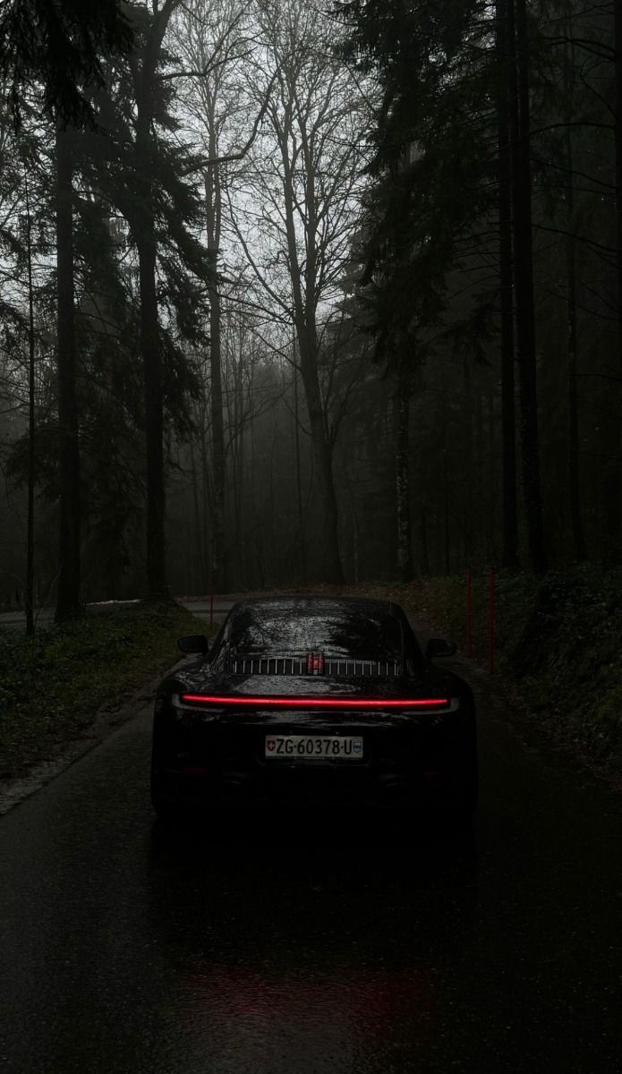 a black sports car parked on the side of a road with trees in the background