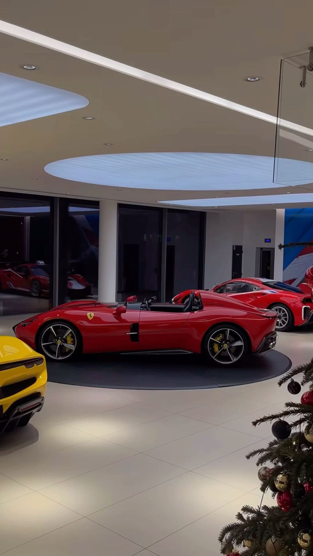 a christmas tree is in the middle of a room with several sports cars on display