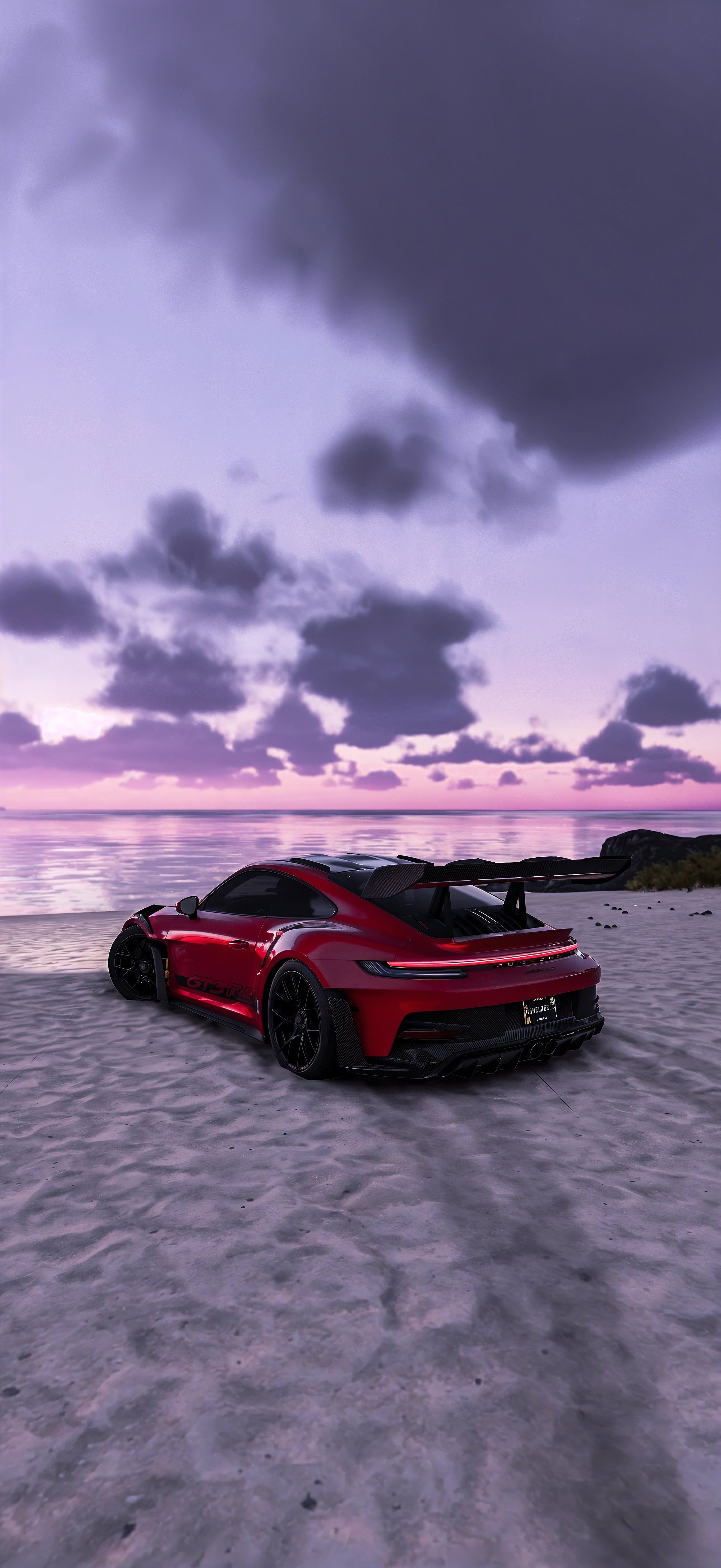 a red sports car parked on top of a sandy beach next to the ocean at sunset