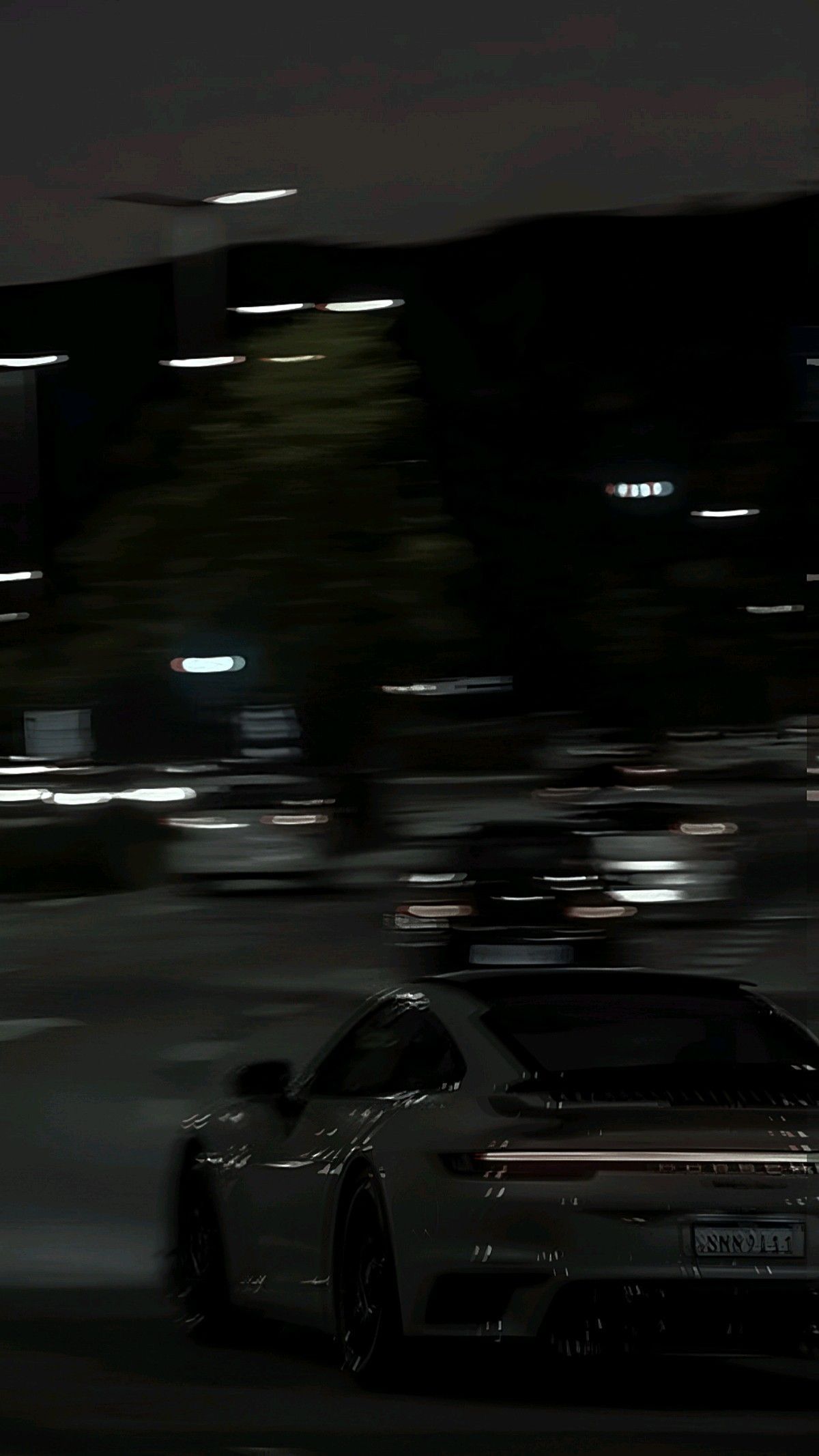 a white sports car driving down a street at night