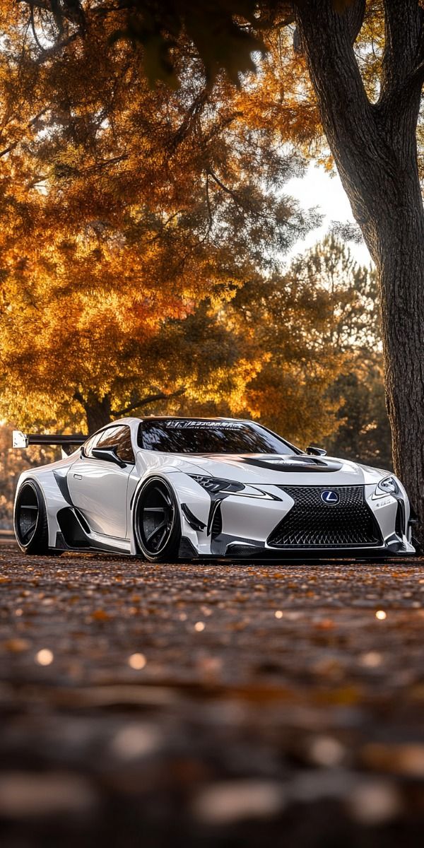 a white sports car parked in front of a tree