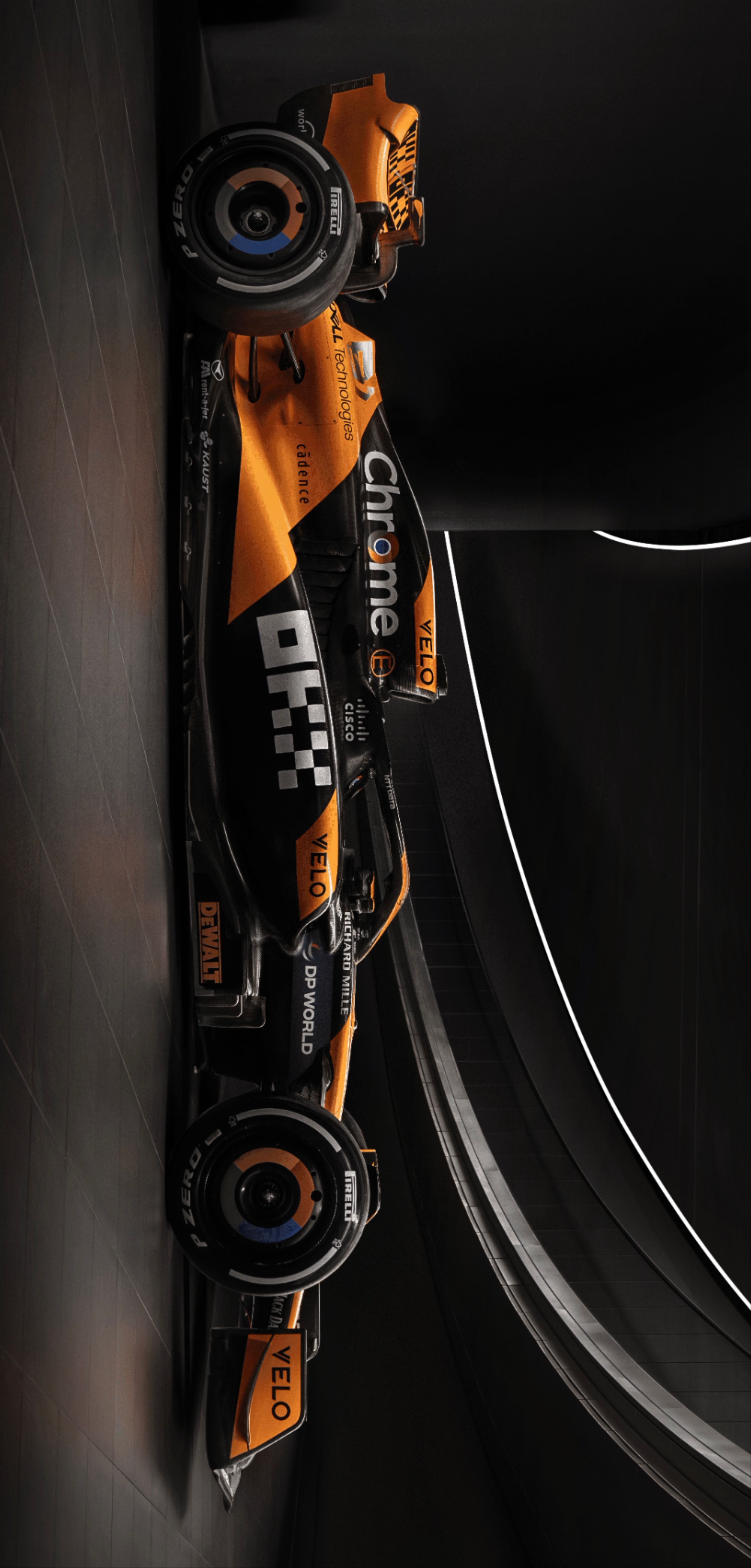 an orange and black race car hanging from the side of a wall in a tunnel