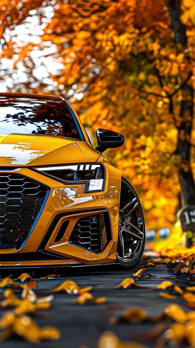 an orange sports car parked on the side of a road in front of trees with yellow leaves