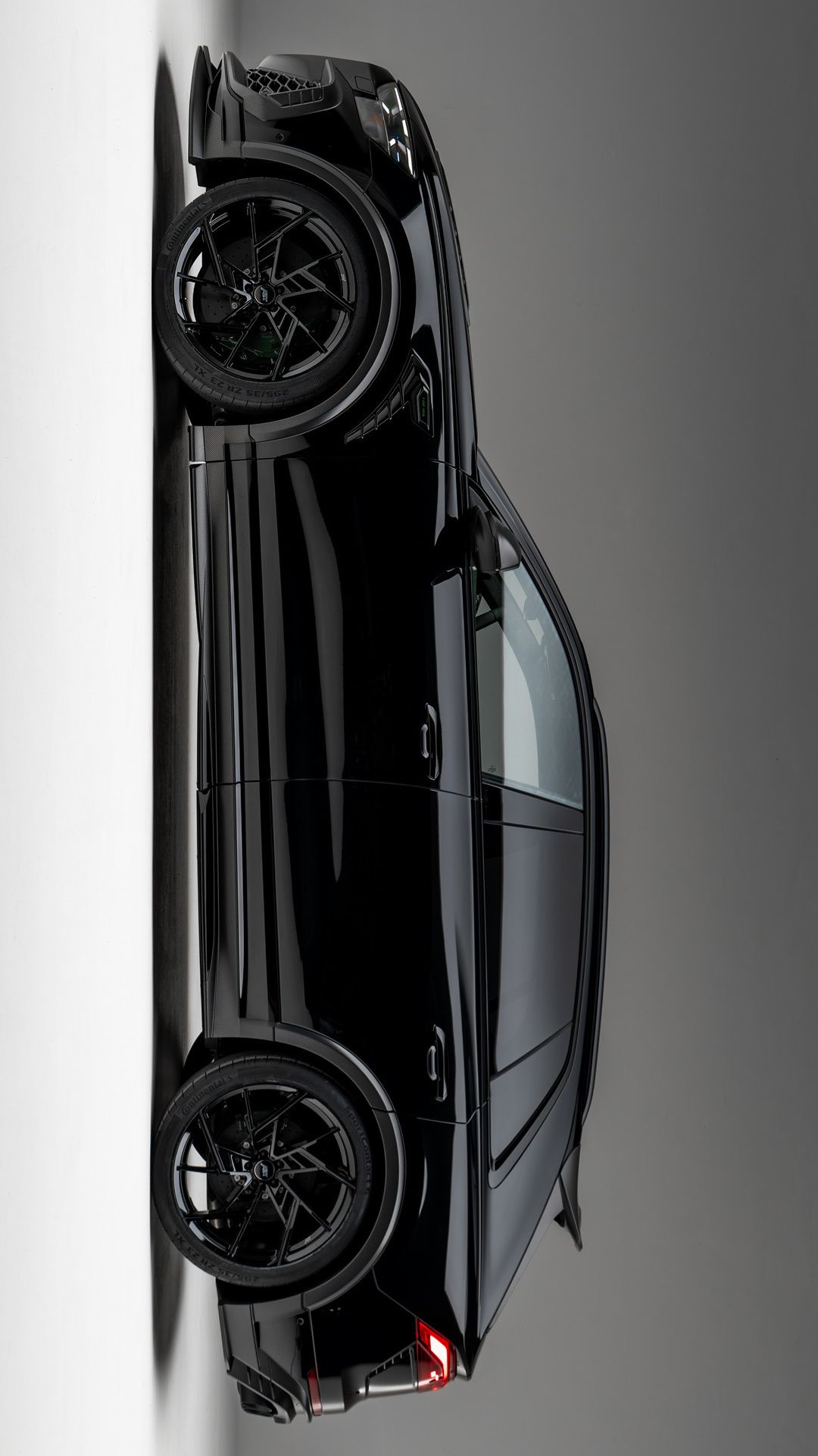 the back end of a black sports car hanging on a wall with its wheels down