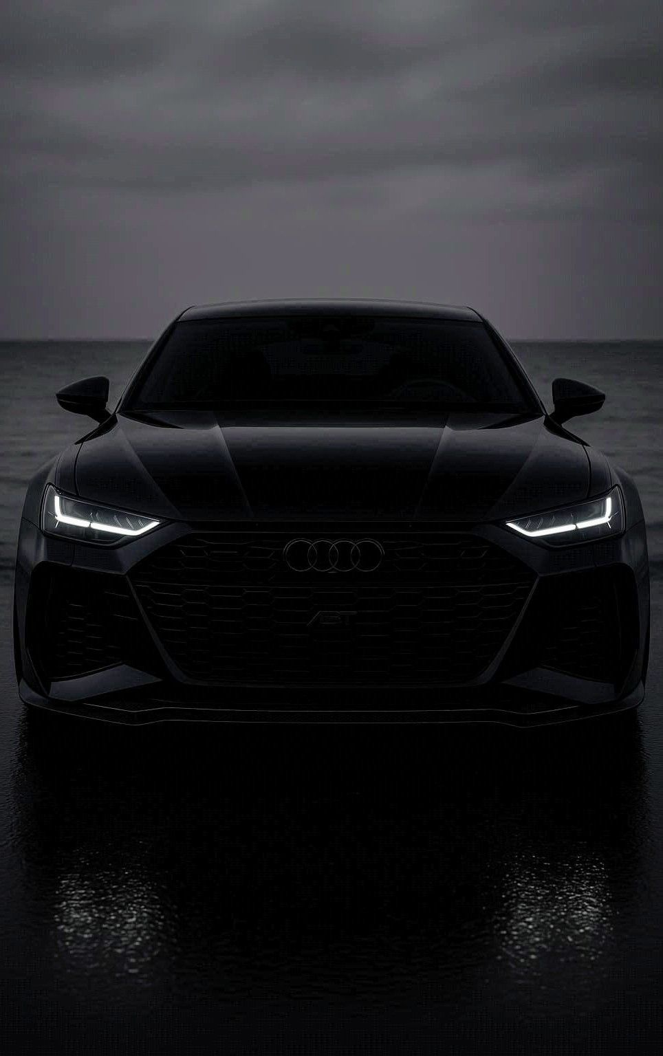 the front end of a black car on a dark beach