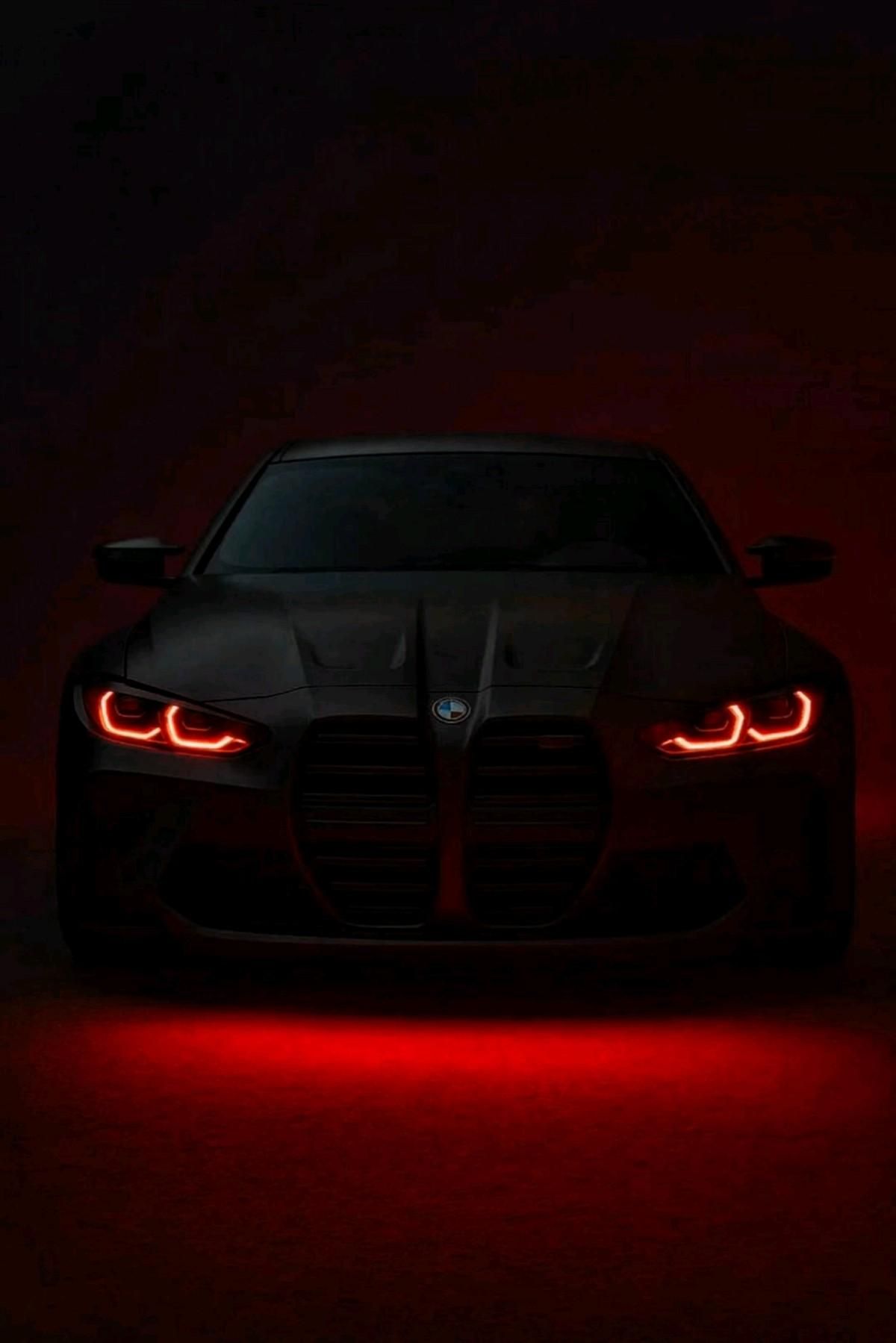 the front end of a black sports car with red lights on it's headlights