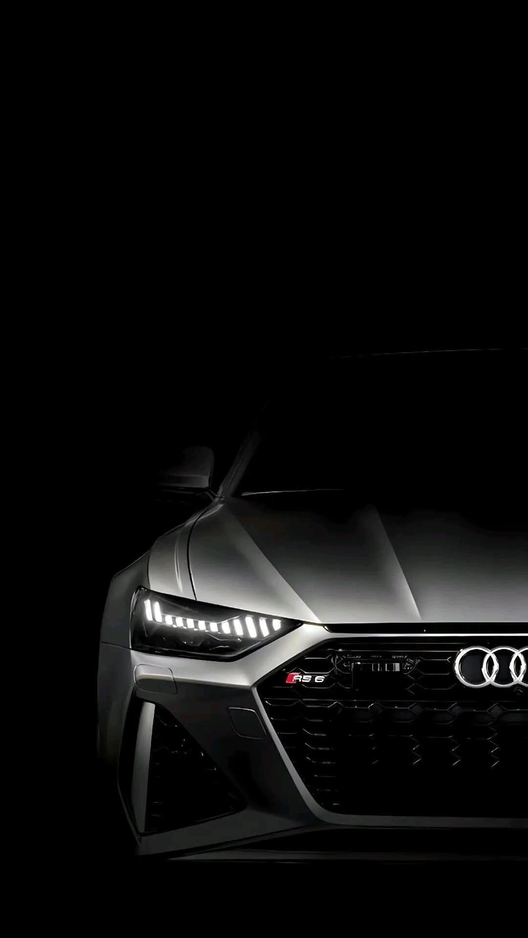 the front end of an audi sports car with its headlights turned on in the dark