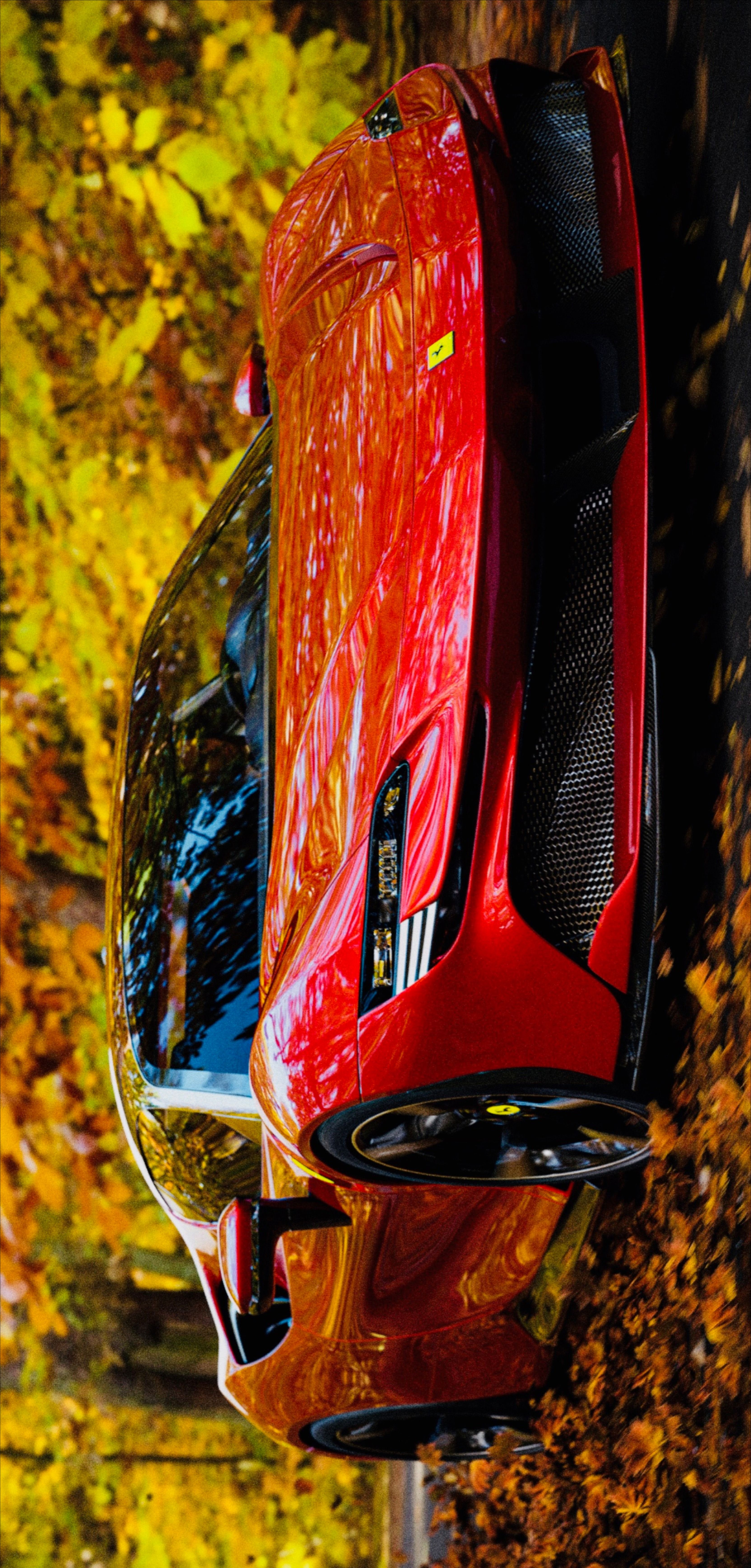 the rear end of a red sports car parked in front of trees with yellow leaves
