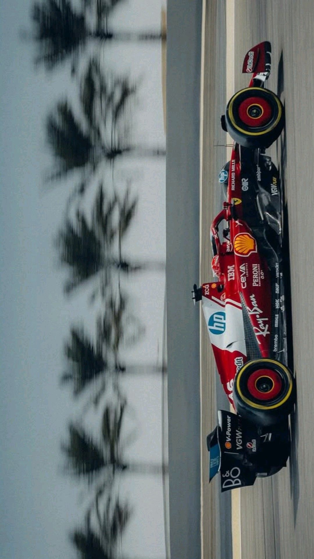 two racing cars driving on a track with trees in the background