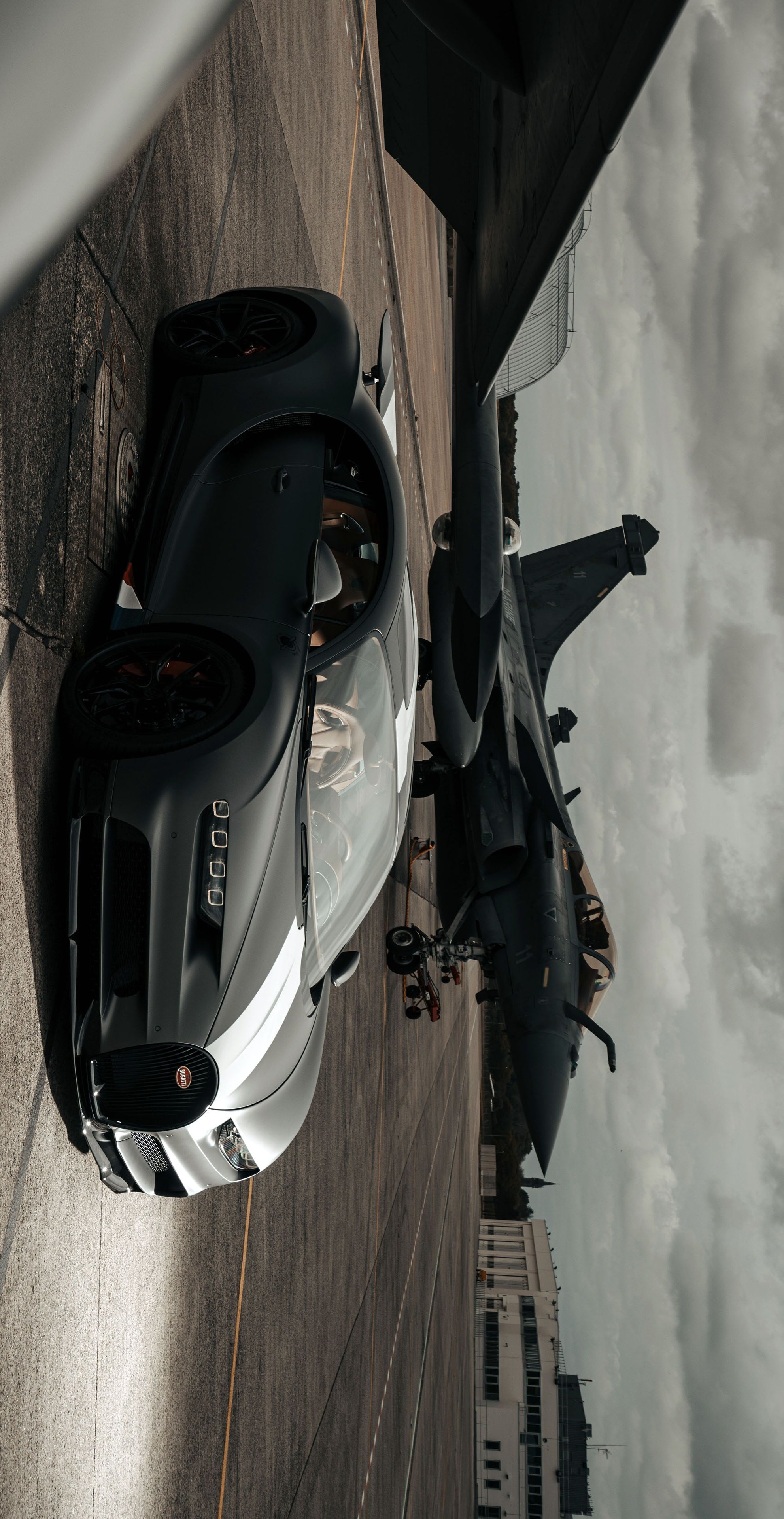 two sports cars parked next to each other on the side of a road in front of a jet
